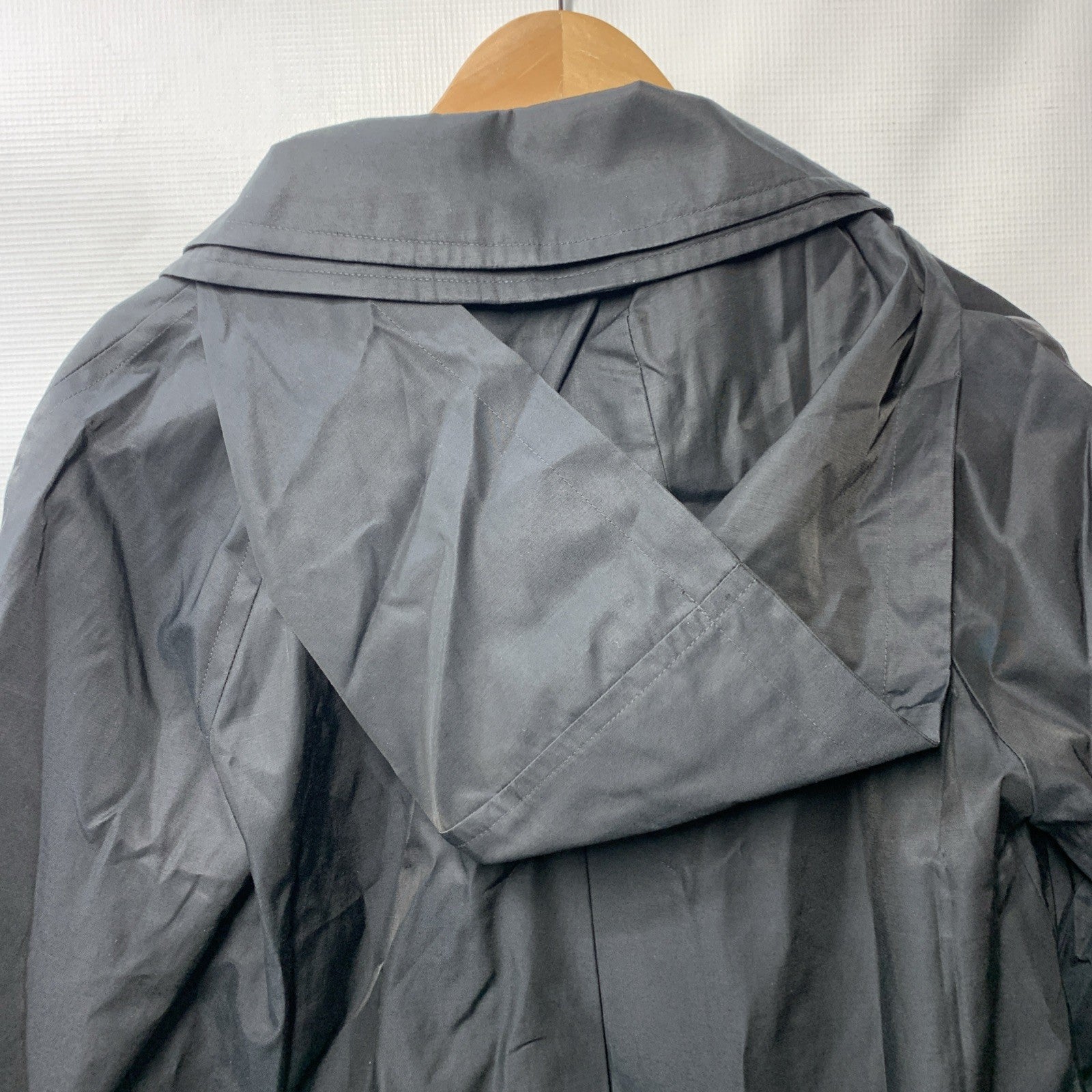 London Fog women's black trench coat with long sleeves, hood, and pockets, shown hanging or styled on a model.